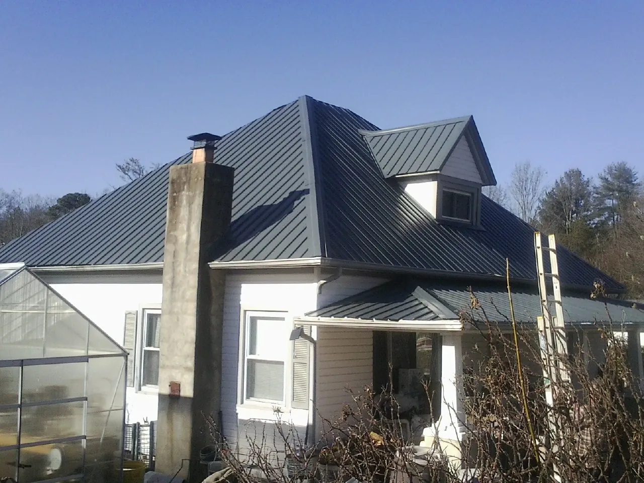 Dark blue standing seam metal roof on a white farmhouse with dormer — Slate & Tile Roof Repair by Roofing Brothers in Tipp City