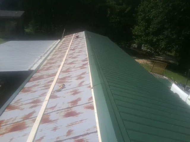 Old rusted panels beside newly installed green metal roofing — Wind Damage Roof Repair by Roofing Brothers in Tipp City