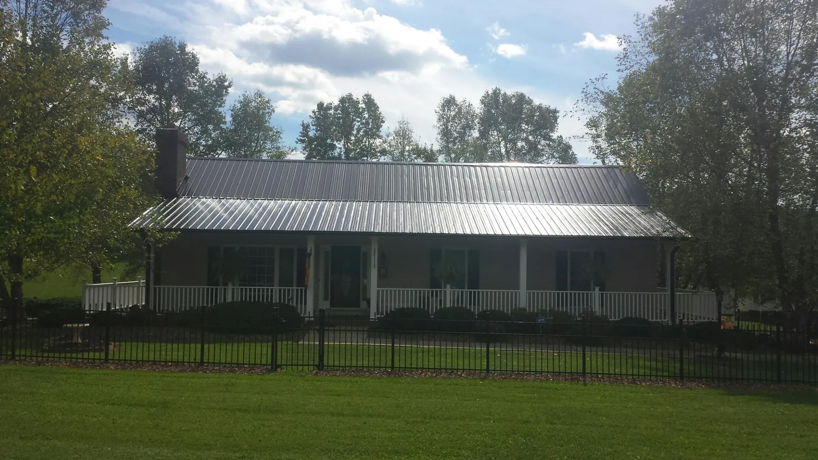 Gray metal roof on a brick ranch with a full width front porch — Gutter Guard Installation work by our crew in Tipp City