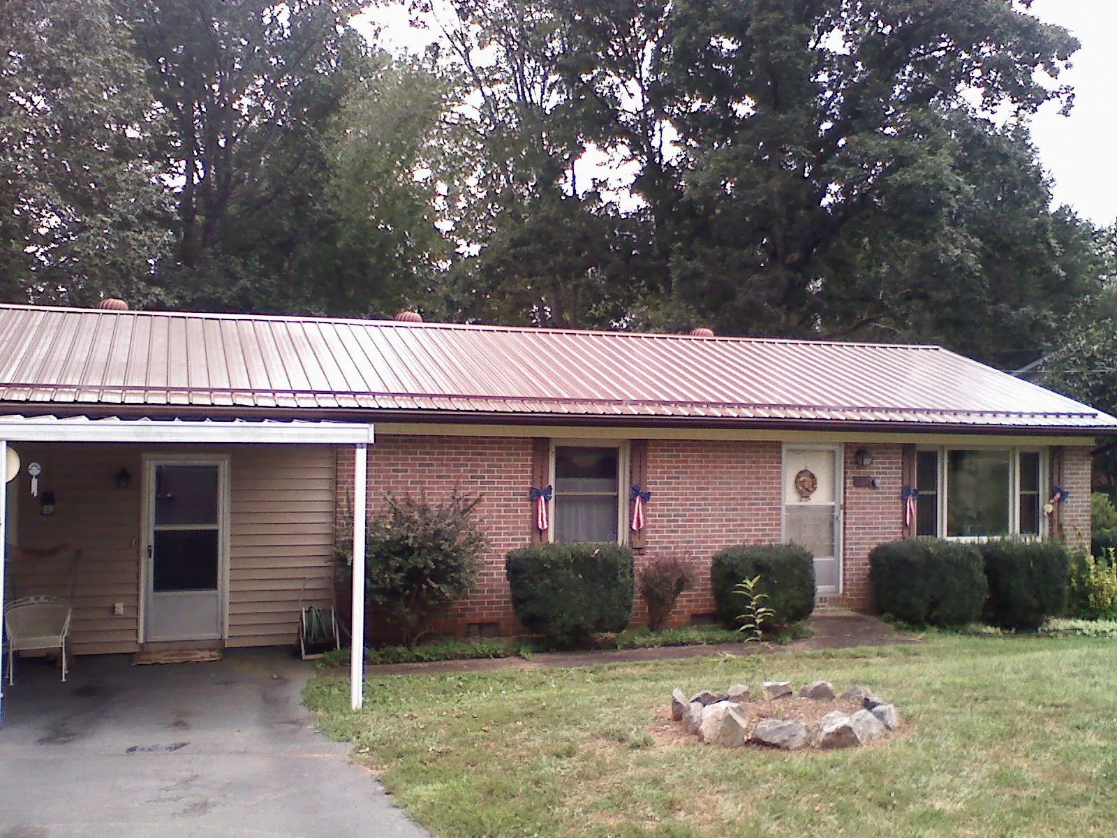 Bronze metal roof and carport on a brick ranch home — Roof Repair work by our crew in Tipp City