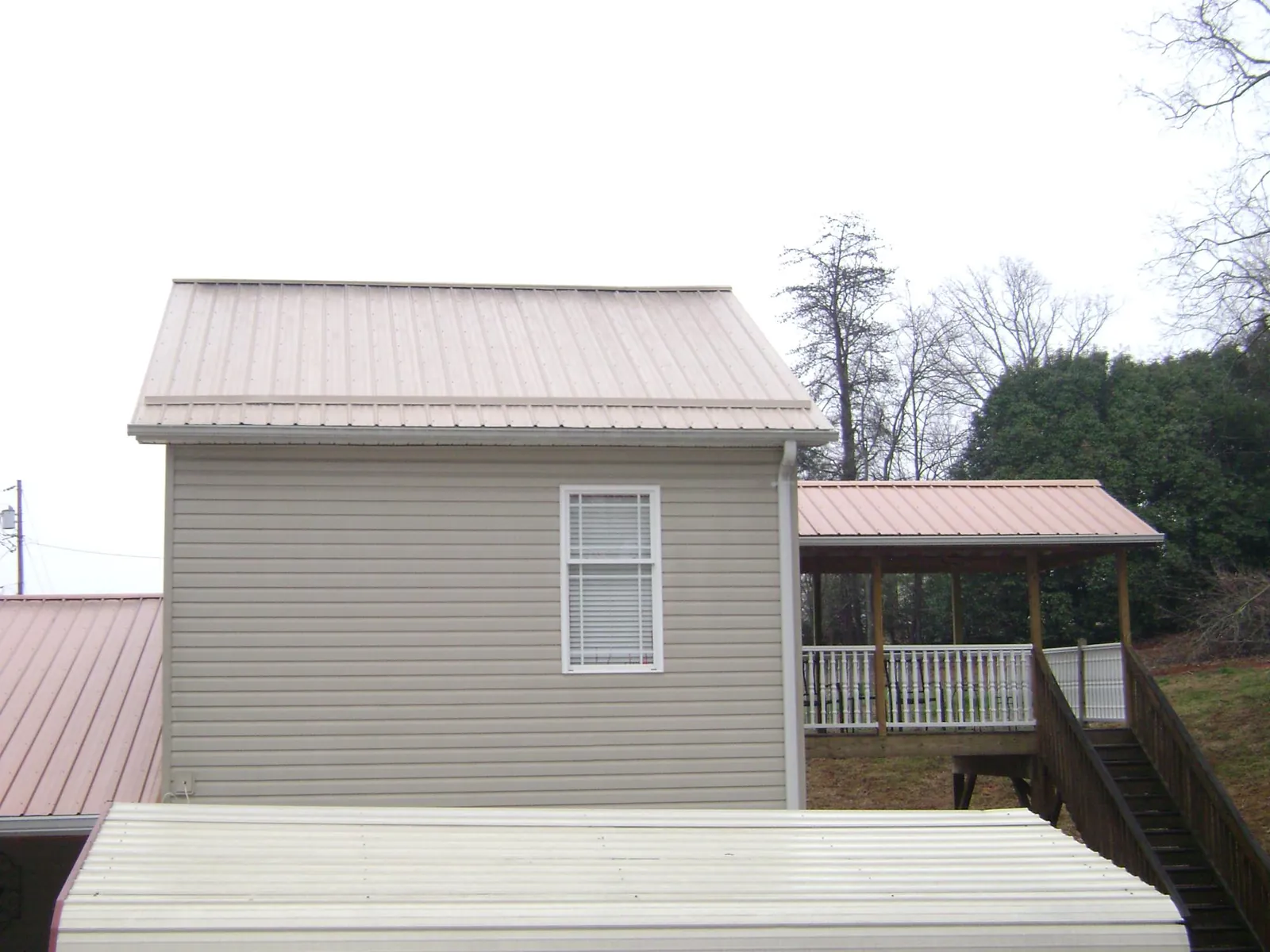 Tan metal roofs on a two story addition and attached porch, from a Roof Replacement job in Tipp City