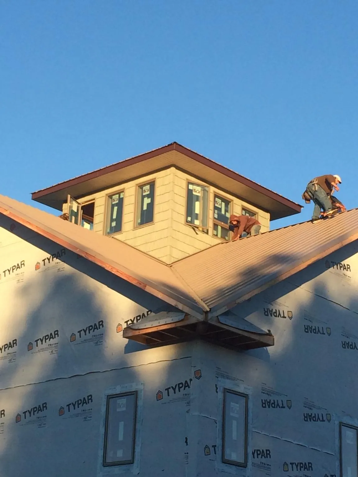 Roofers working around a rooftop cupola on a new metal roof at sunset — Roof Waterproofing in Tipp City by Roofing Brothers